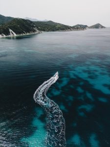 Gommone in navigazione lungo la costa nord dell'Isola d'Elba tra falesie chiare e mare turchese, noleggio gommoni Rent Boat Bagnaia